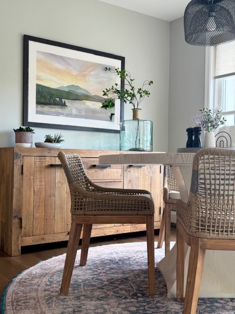 Breakfast nook with woven dining chairs, landscape art, wood buffet, and patterned rug