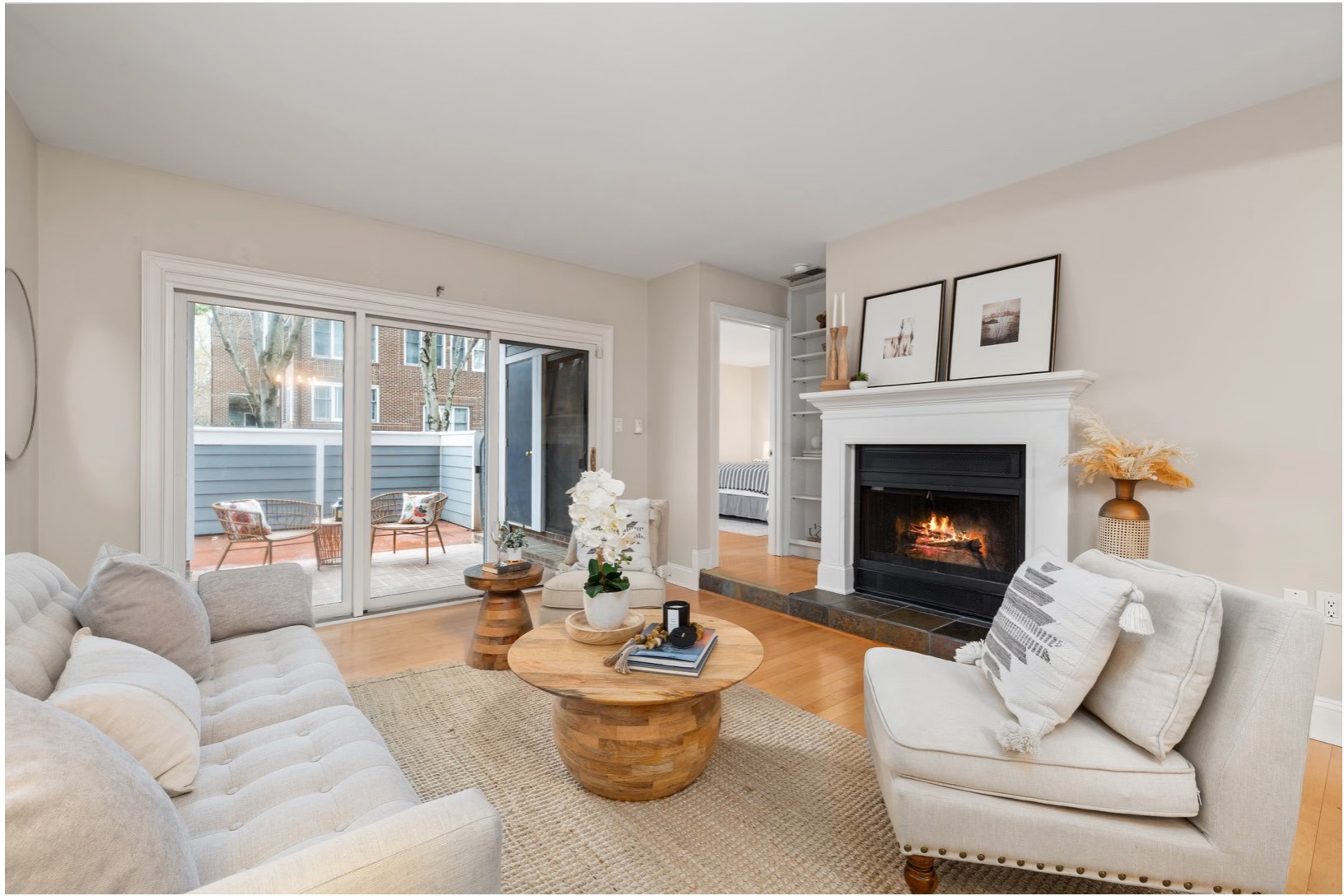 Bright neutral living room with cream seating, warm wood tables, and a white fireplace